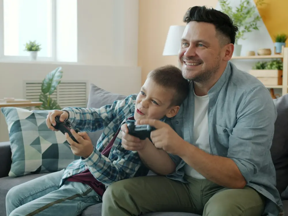 A father and son laughing while playing a video game together