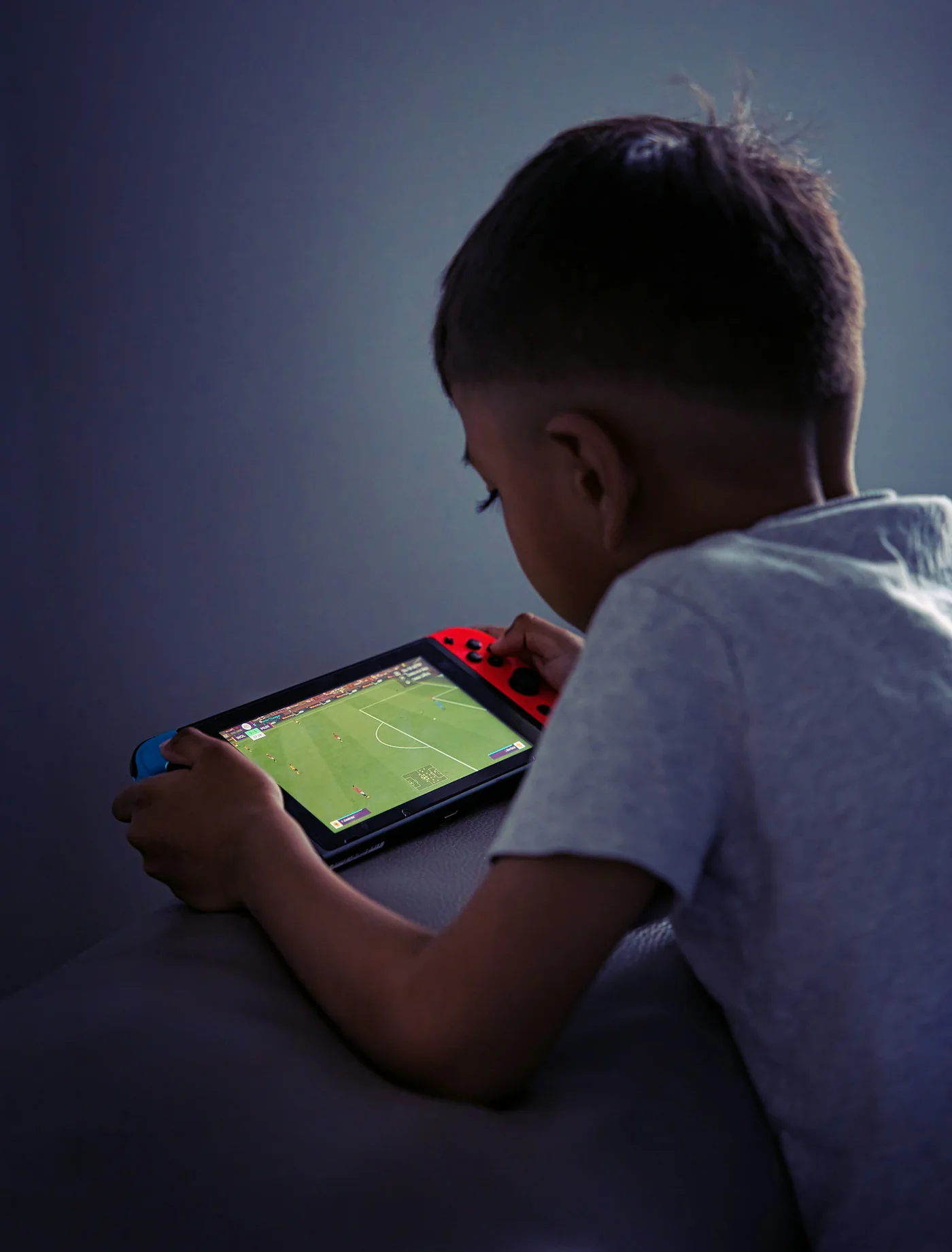 A boy absorbed in a handheld game in the evening